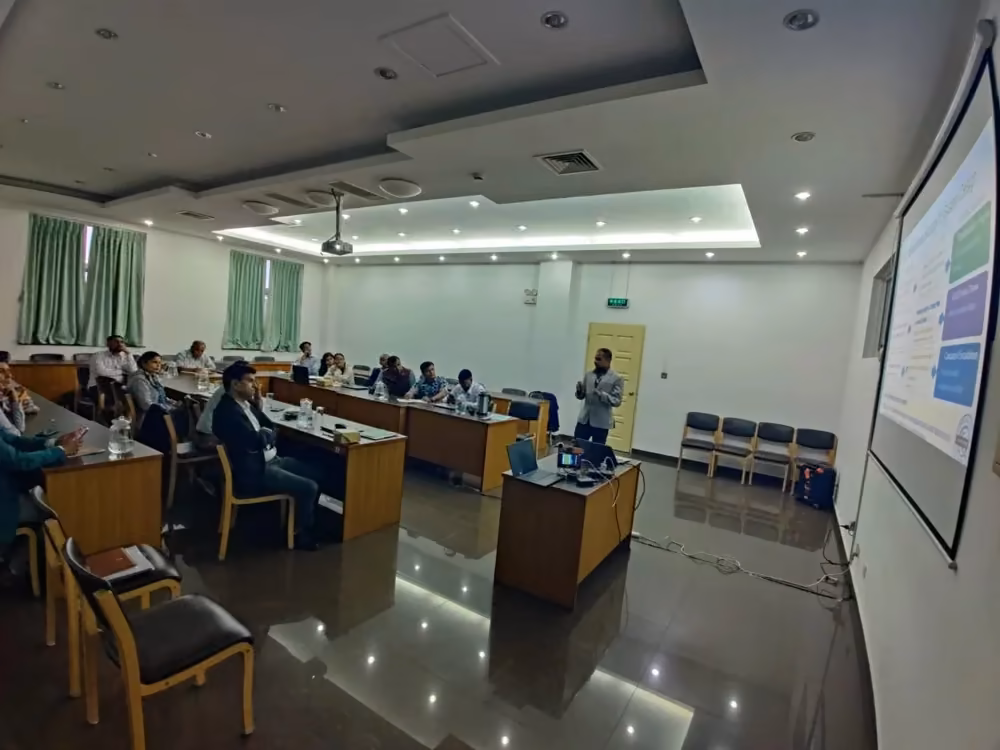 A seminar room of long desks facing a projected slide, a few people seated
