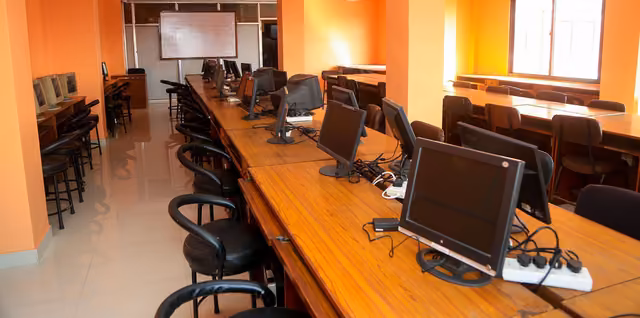 Monitors ranged along two long tables in the computer laboratory, a screen at the far end
