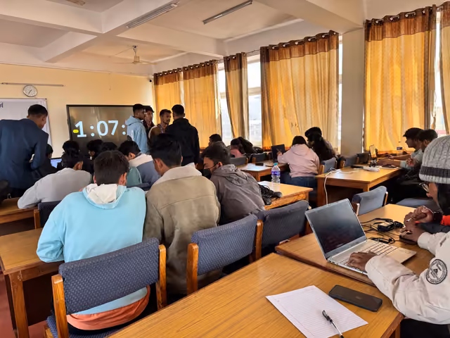 Students at laptops round tables with a countdown clock on the screen behind